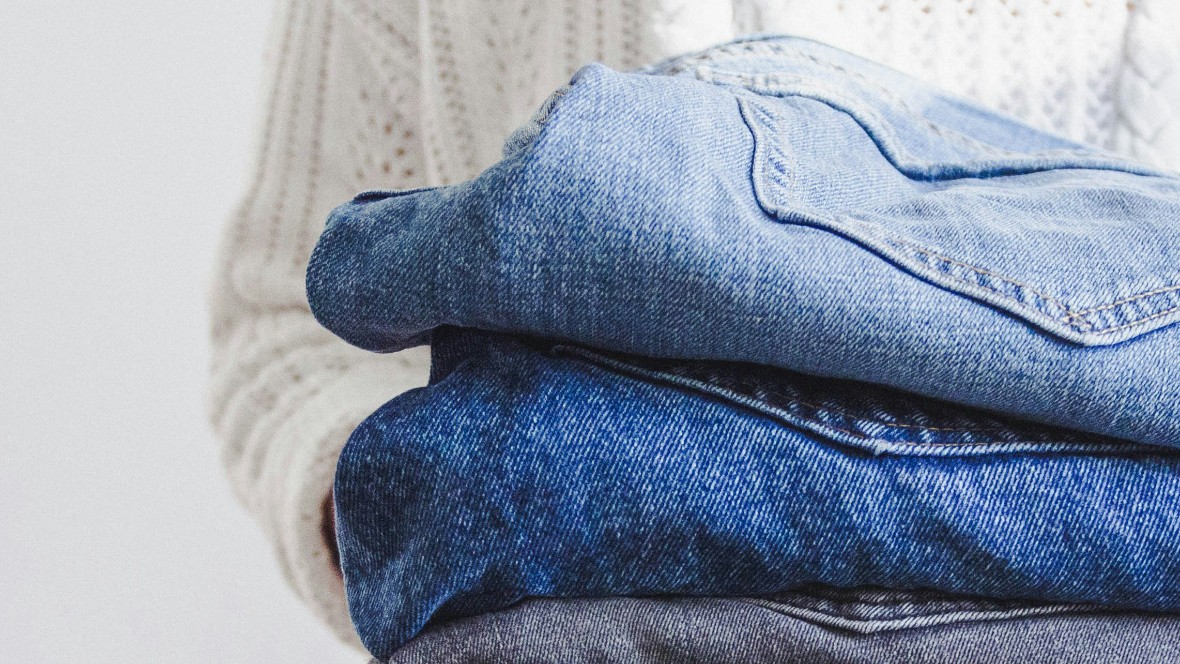 Person håller en trave med jeans