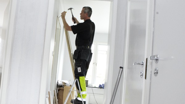 Man på stege fixar i en lägenhet